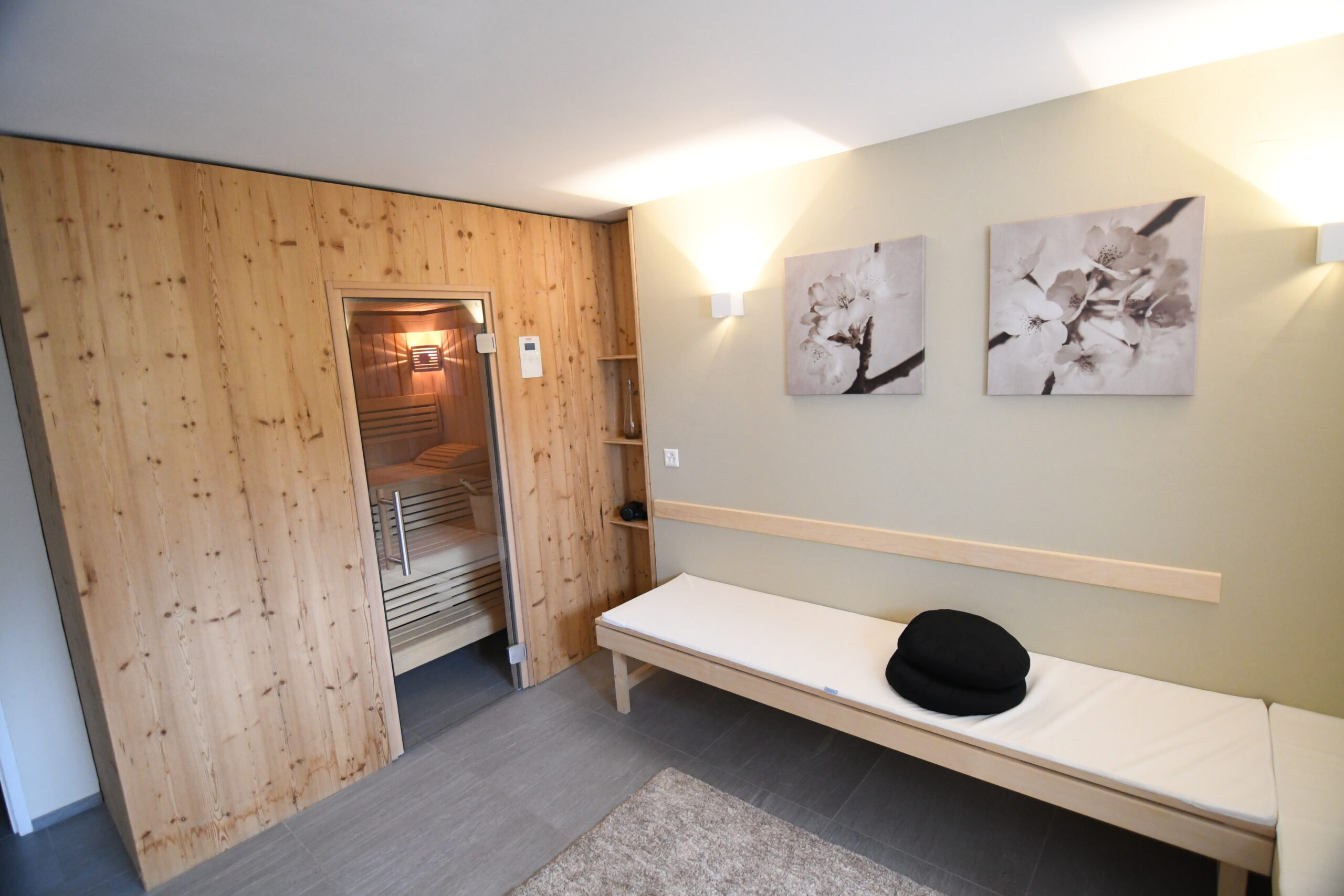 Modernes Wellness-Zimmer mit Holzsauna, Ruhebank und Wanddekoration.