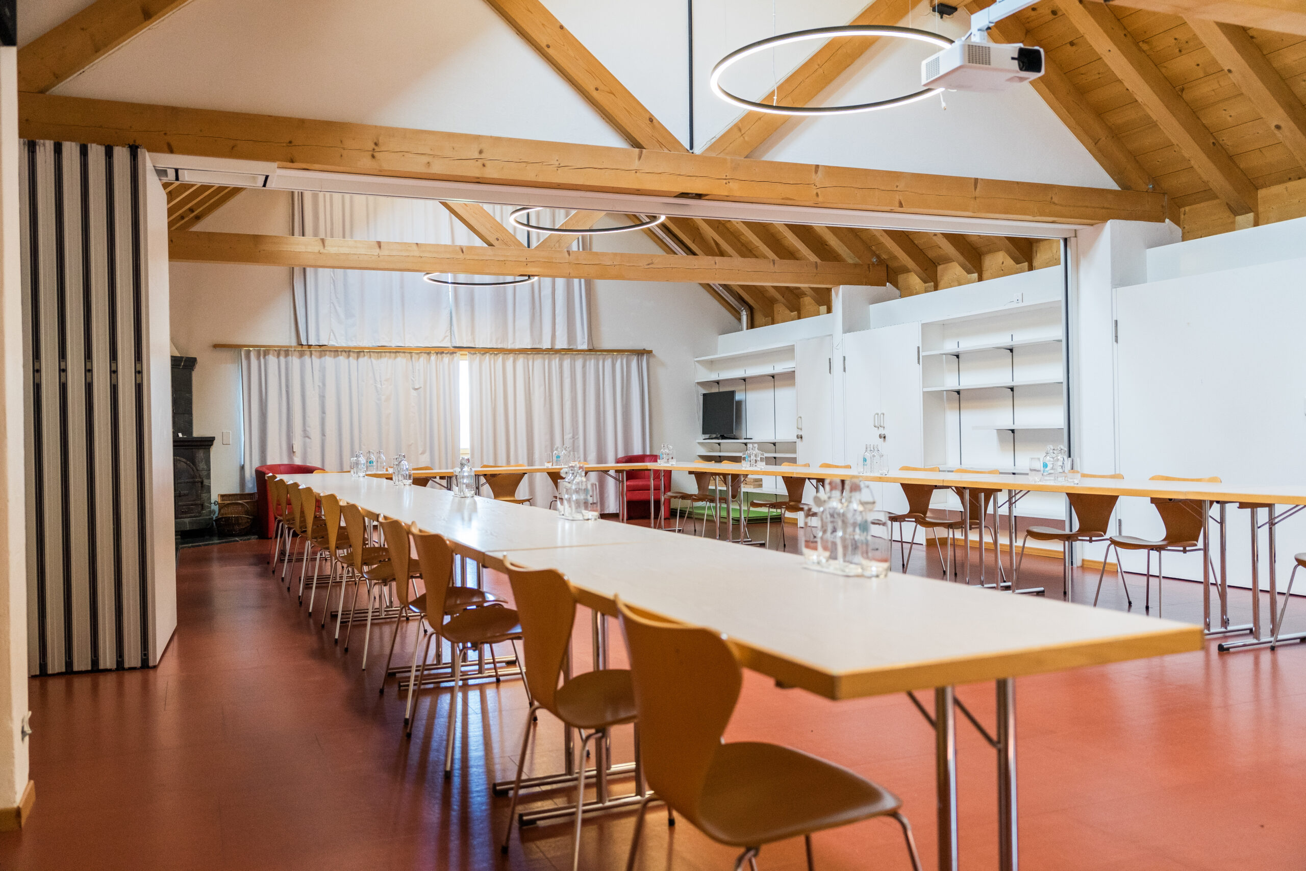 Moderner Konferenzraum mit Holzbalkendecke und U-förmiger Tischanordnung.