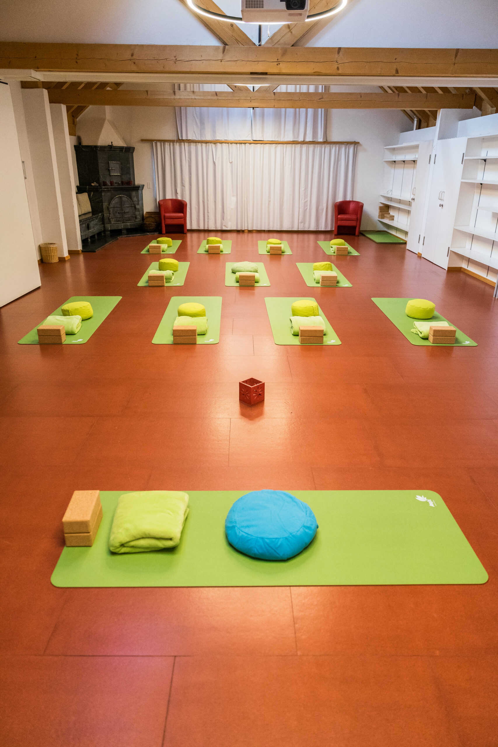 Vorbereiteter Yoga-Raum mit grünen Matten und Meditationskissen